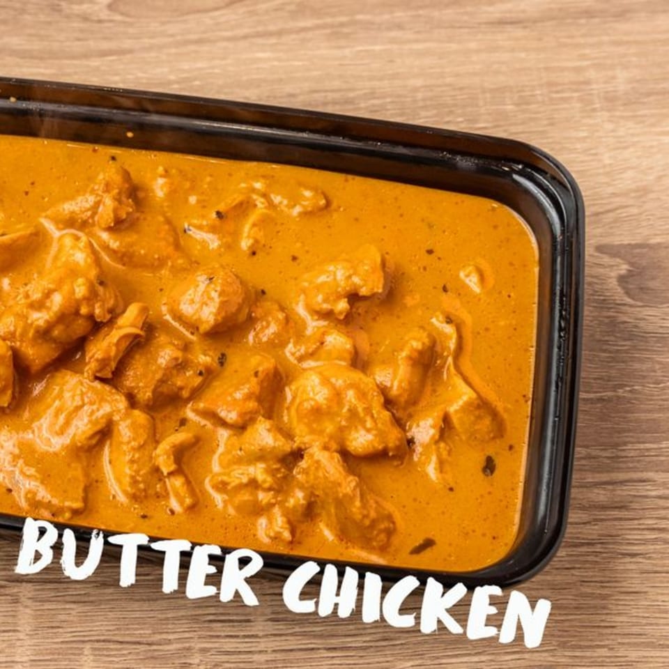 Kolapasi Indian Canteen's butter chicken, a rich orange curry with chicken pieces in a black container.